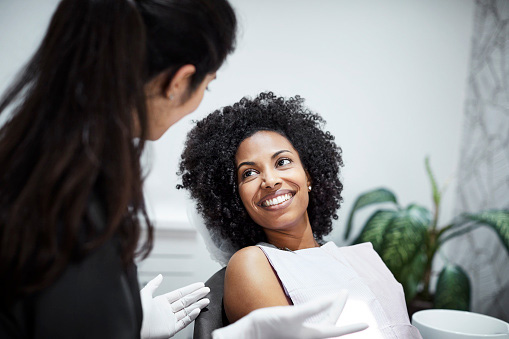  Dentist discussing tooth loss with smiling female patient at Stamford Oral & Maxillofacial Surgical Arts in Stamford, CT 06905-4501
